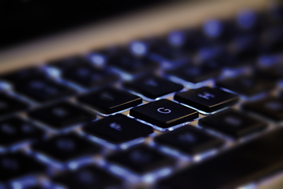 Foto de um teclado preto, com luzes azuis saindo debaixo das teclas