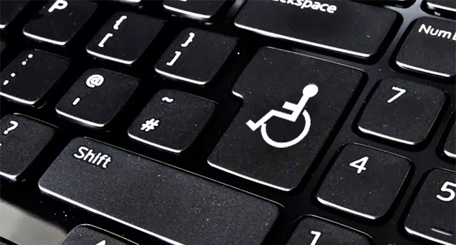 Close em um teclado de computador que mostra o símbolo da pessoa com deficiência no lugar do enter.