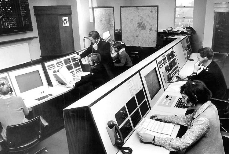 Foto em preto e branco com central de atendimento telefônico norte-americano, com centrais antigas e telefonistas