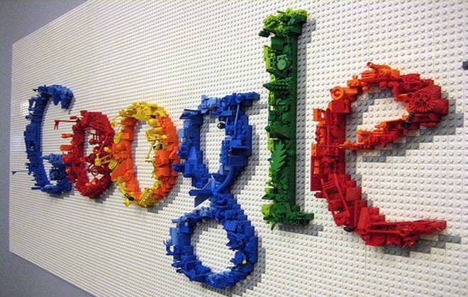 Foto de um painel de Legos do tamanho de uma parede, com o logotipo formando a palavra Google com peças de lego nas cores azul, vermelho, verde e amarelo
