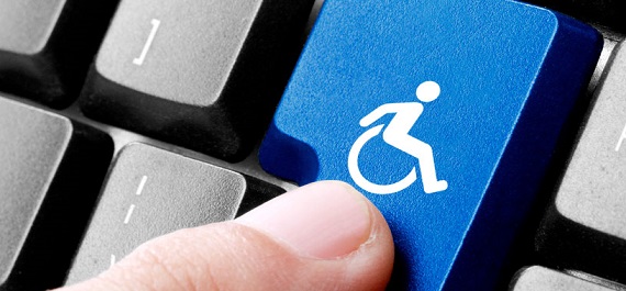 Foto em close de um teclado de computador. Um dedo aciona a tecla enter que tem o símbolo da deficiência física