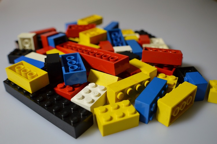 Foto de blocos coloridos de LEGO nas cores azul, amarelo, branco, preto e vermelho espalhados em uma superfície